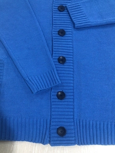 Detail of royal blue men's knitted cardigan showing ribbed cuffs and resin buttons
