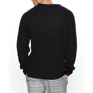 Rear view detail of black waffle knit sweater showing ribbed cuffs and hem on white background