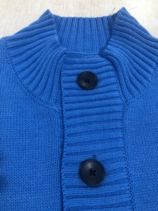 Detailed close-up of blue knit cardigan with ribbed collar and black round buttons