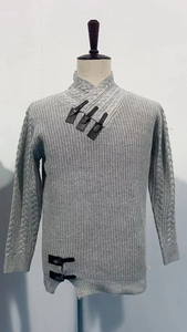 Close-up of light grey knit sweater showing leather buckle neck and cable knit sleeves