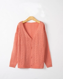 Detail of coral orange V-neck knit cardigan with hollow out pattern and ribbed cuffs