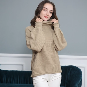Dettaglio del collo alto e polsini a costine su maglione lavorato a maglia beige