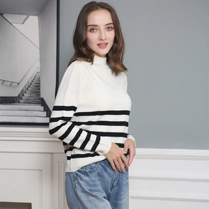 Detail of three gold decorative buttons on the shoulder of a striped turtleneck knit sweater