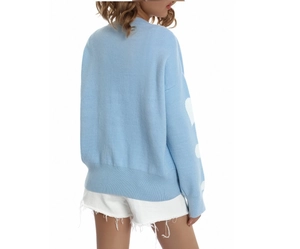 Detail of light blue knit sweater featuring a white heart pattern on the cuff and soft texture