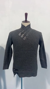 Detail of grey knitted sweater with leather buckle fasteners and cable knit texture