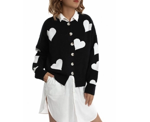 Detail of black knit cardigan with white heart patterns and amber buttons in close-up