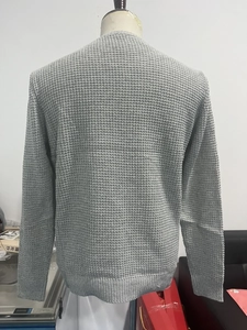 Detail of grey men's waffle knit sweater showing textured pattern and ribbed hem