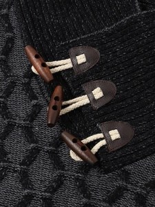 Detail of grey cable-knit sweater featuring vintage faux leather and toggle button closures