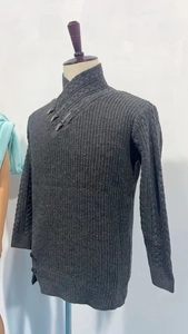 Macro detail of dark grey cable-knit sweater with leather buckle and thick knit texture