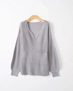Détail du pull en maille grise avec col en V, texture ondulée et taille marquée à côtes