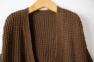 Detail of dark brown knit cardigan with waffle texture on wooden hanger