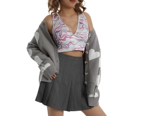 Detail of grey knitted cardigan with white heart pattern over pink crop top and pleated skirt