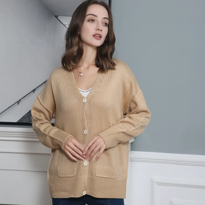 Detail of camel knit cardigan with V-neck, white buttons and practical front pockets