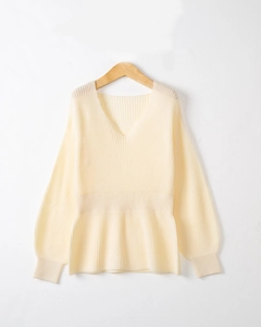 Détail du pull en maille beige avec col en V, taille cintrée et texture douce côtelée