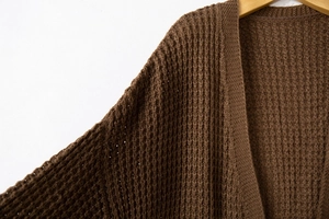 Close-up of deep brown chunky knit cardigan featuring waffle weave texture and drop shoulder