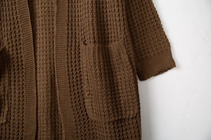 Detail of waffle knit texture and large front pocket on long brown cardigan sweater