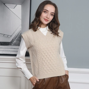 Detail of beige V-neck knitted vest showing intricate cable knit patterns and diamond texture