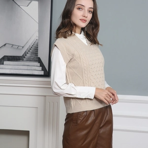Detail of beige V-neck cable knit vest layered over a white shirt for a chic look