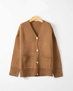 Detail of V-neck knit cardigan featuring large front pockets and white button closure