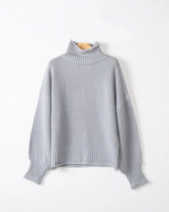 Dettaglio del maglione grigio chiaro a collo alto con texture a maglia e bordi a coste
