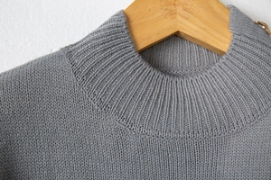 Detail of grey striped turtleneck sweater showing ribbed collar and gold shoulder buttons