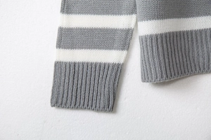Detail of grey and white striped knit sweater with ribbed cuffs and soft texture