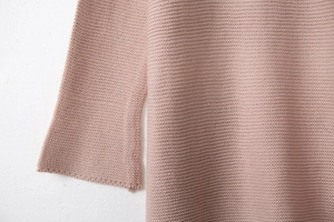 Close-up of pink knit sweater showing fine ribbed texture and clean cuff stitching detail