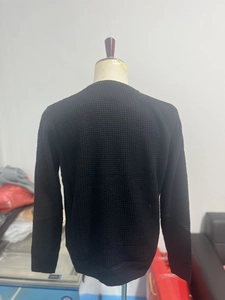 Macro shot of black long-sleeve waffle knit sweater featuring honeycomb texture detail