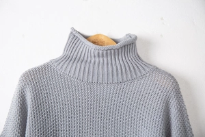 Dettaglio macro di un maglione a collo alto grigio con maglia spessa e trama a quadretti