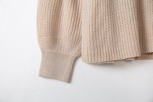 Détail des poignets côtelés et texture en maille de qualité sur ce pull beige à col en V