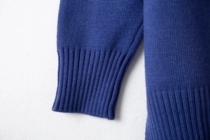 Detailed view of the royal blue knit texture and elastic ribbed cuffs on the sweater