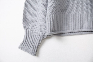 Dettaglio del maglione grigio chiaro con trama a nido d'ape e polsini a costine