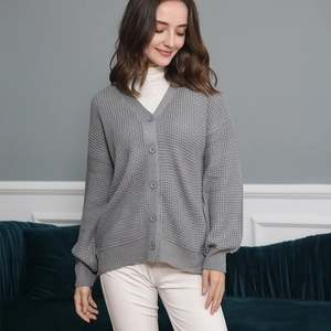 Dettaglio del cardigan grigio con maglia a nido d'ape, scollo a V e bottoni tondi
