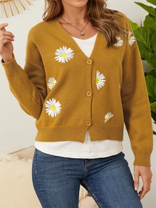 Detail of daisy flower embroidery and buttons on mustard yellow knit cardigan
