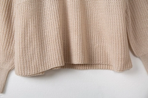 Gros plan des poignets et de l'ourlet en maille côtelée épaisse sur ce pull beige femme