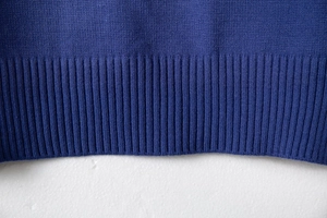 Close-up of the dark blue knit sweater showing detailed ribbed knit hem and texture