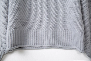 Dettaglio ravvicinato di un maglione grigio a maglia grossa con orlo a coste di alta qualità