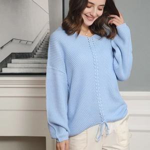 Detail view of light blue v-neck knit sweater featuring crochet heart texture and drawstring hem