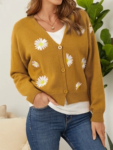 Detail of embroidered daisies and matching buttons on mustard yellow knit cardigan