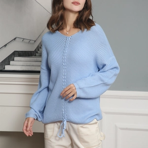 Macro shot of light blue knit sweater featuring V-neck and front drawstring hem detail