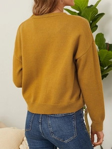 Back view of mustard yellow knit sweater featuring ribbed cuffs and dropped shoulders