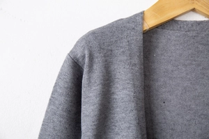 Close-up of the fine grey knit fabric and neckline stitching on this casual cardigan