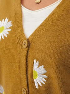 Detail of mustard yellow knit cardigan with white daisy embroidery and resin buttons