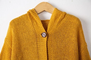 Détail d'un cardigan à capuche en maille épaisse jaune moutarde avec bouton en bois vintage