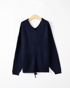 Detail of navy knit sweater featuring a wide V-neck and adjustable drawstring hemline
