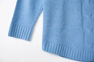 Close-up detail of light blue cable knit texture and ribbed cuffs on the sweater