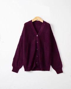 Dettaglio della maglia a nido d'ape e dei bottoni in resina su un cardigan viola scuro