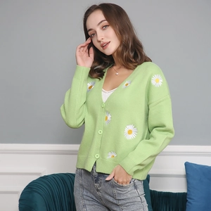 Detail of light green knit cardigan featuring white daisy embroidery and V-neckline button closure