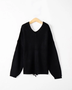 Detail of black V-neck knit sweater showing central seam and bow tie at the bottom hem
