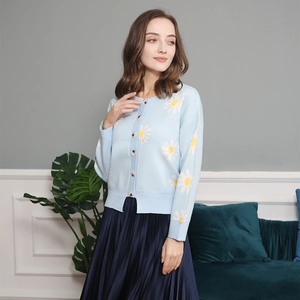 Detailed knit texture of light blue cardigan featuring white daisy floral embroidery